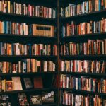 Corner view of a library with dark wooden bookshelves filled with a variety of books.